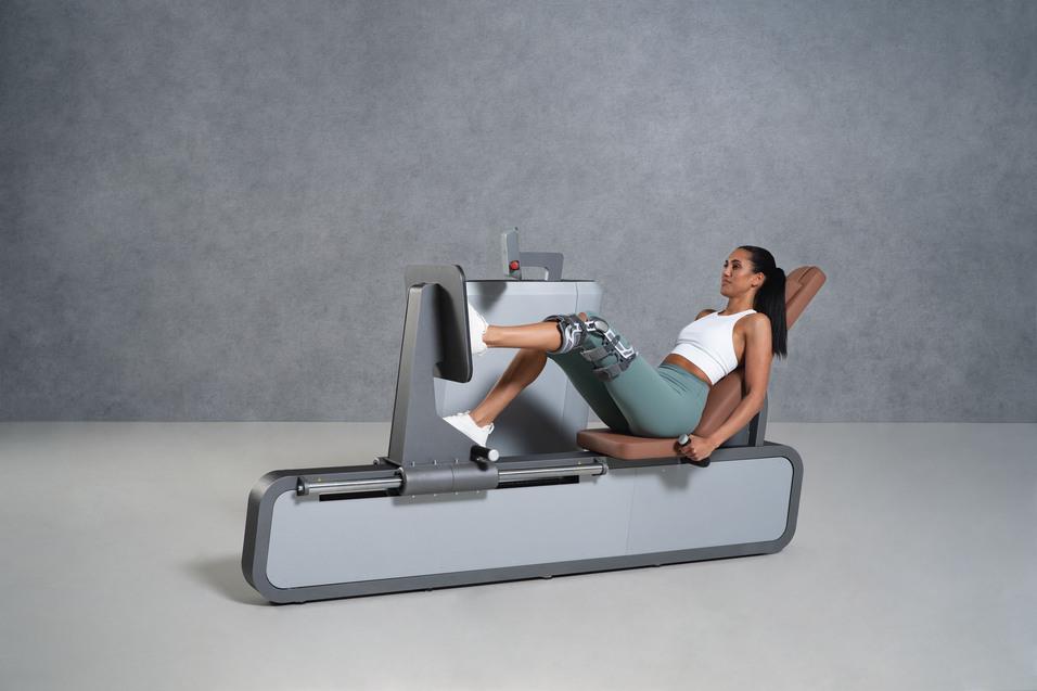 Frau im Sportoutfit trainiert an einer Beinpressmaschine in einer modernen Fitnessumgebung.
